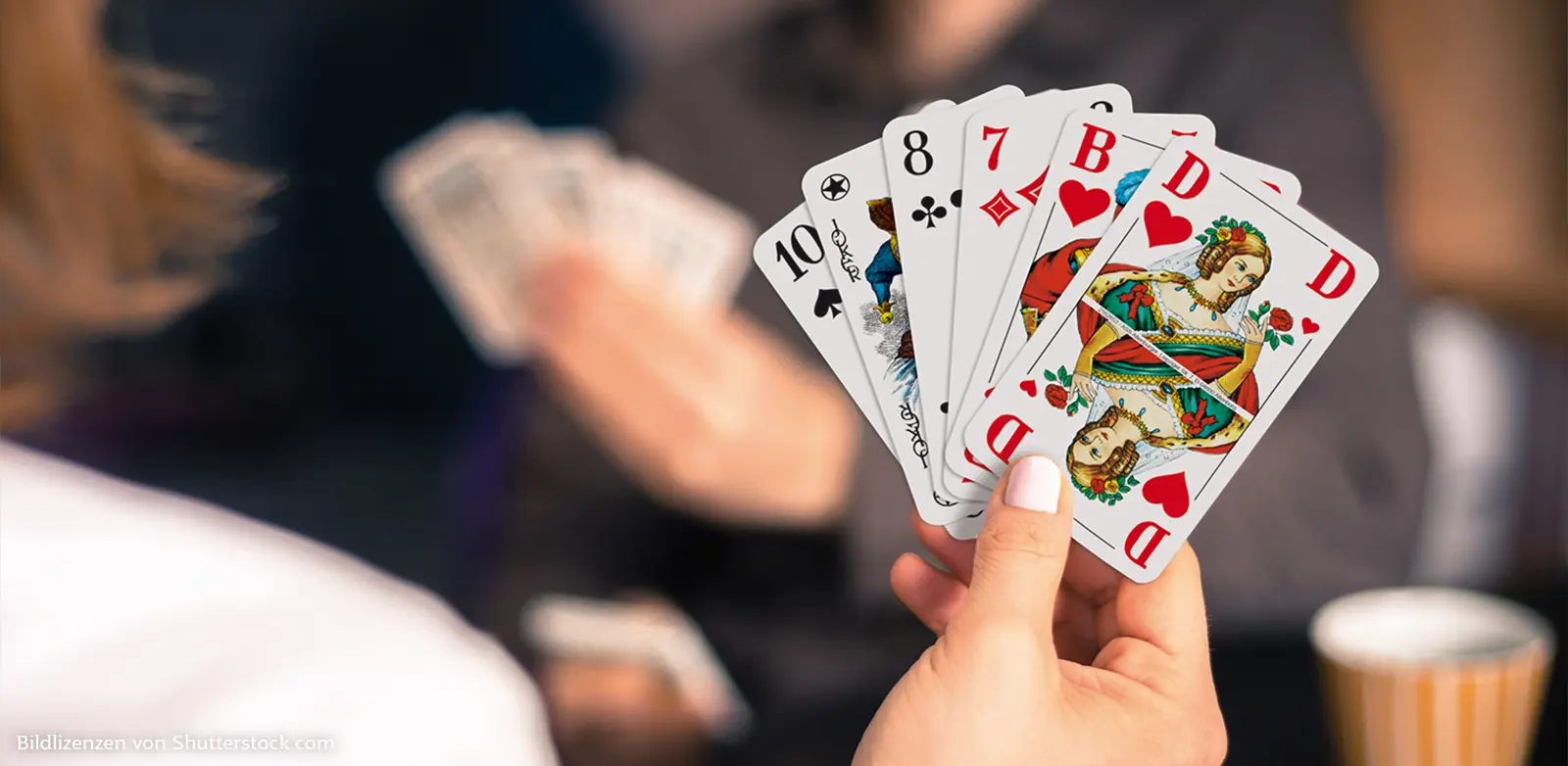 Ein Hand hält sechs Karten des Kartenspiels Senioren Rommé. Rommé, ASS Altenburger